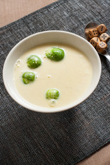 Smoked cheese and pumpkin puree soup with brussels sprouts. In bowl on grey tablecloth.