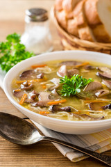 Chicken soup with mushrooms and noodles on rustic wooden table