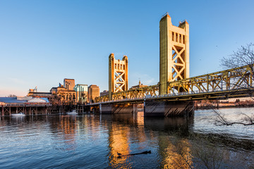 Gold Tower Bridge in Sacramento, Kalifornien bei blauem Sonnenuntergang mit Innenstadt und Gans auf schwimmendem Baumstamm