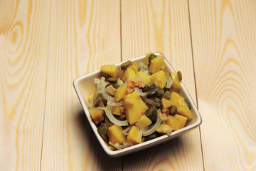 Potato salad in bowl on wooden table