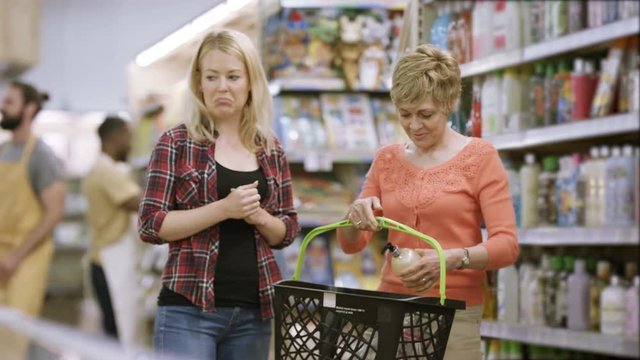  Mother & daughter shopping in frozen food aisle of supermarket