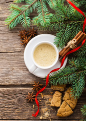 A cup of coffee with the branches of the Christmas tree on a wooden table