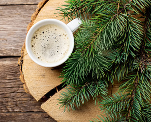 Obraz na płótnie Canvas A cup of coffee with the branches of the Christmas tree on a wooden table