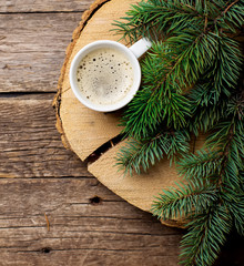 A cup of coffee with the branches of the Christmas tree on a wooden table