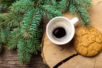 A cup of coffee with the branches of the Christmas tree on a wooden table