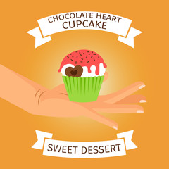 Hand holding cupcake with chocolate heart,