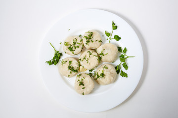 Khinkali on white plate with parsley and  dill