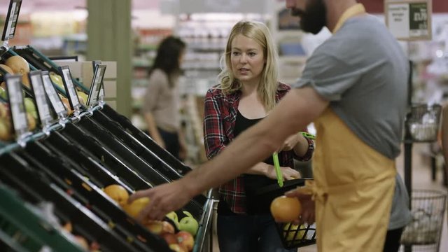  Friendly worker in a supermarket assisting young woman buying groceries