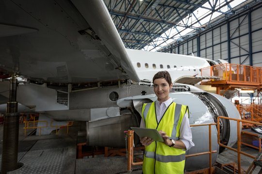 Female aircraft maintenance engineer using digital tablet