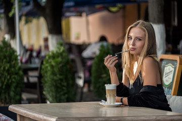 girl plays with spoon and coffe in cafe