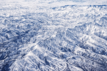 Fototapeta na wymiar Alchemy of spring, mountains in spring: snow remains on Northern slopes and formed a beautiful forest of branching gorges - dendrogram. View from height, air photography.