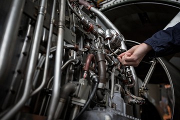Male aircraft maintenance engineer examining turbine engine of