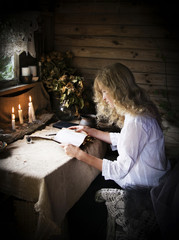 Girl reading a book in the magical mystical ancient dark room with candles
