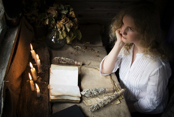 Girl reading a book in the magical mystical ancient dark room with candles