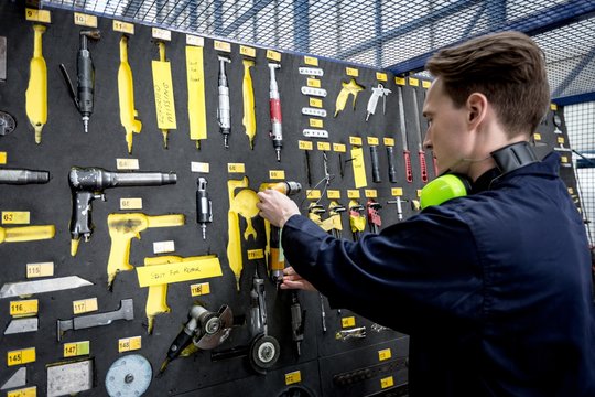 Male aircraft maintenance engineer examining various work tool