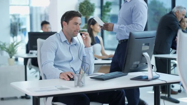 Call centre operators in city office working on computers talking to customers
