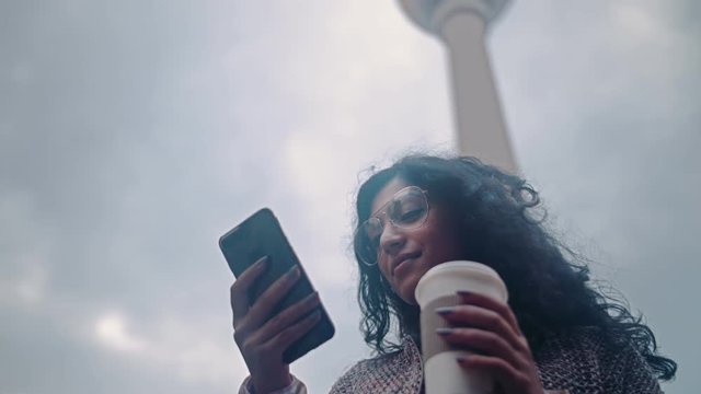Beautiful Mixed race woman using smart phone technology app living urban happy lifestyle on the background of the Berlin TV tower