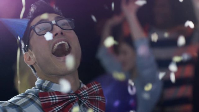 Happy nerdy guy dancing and throwing confetti at party