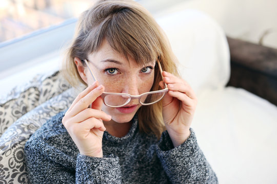 Woman taking out her glasses and looking at the camera