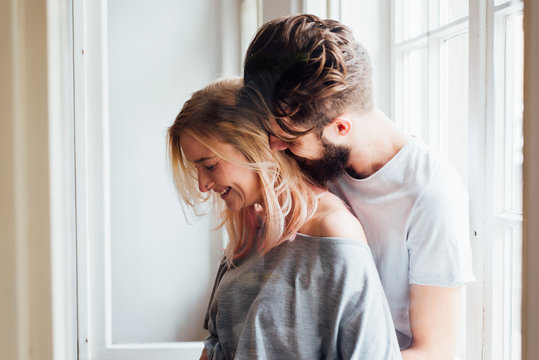 Blond Woman Smiling While Her Boyfriend is Hugging Her