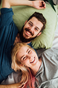 Happy Couple In Smling While Lying in Bed