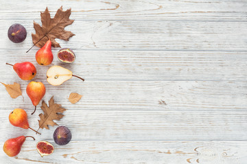 Abstract composition of fresh ripe fruits and leaves on a white wooden background.