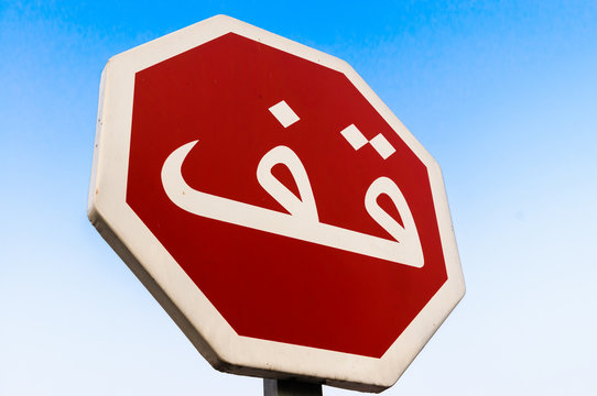 Arabic stop road sign against a blue cloudless sky