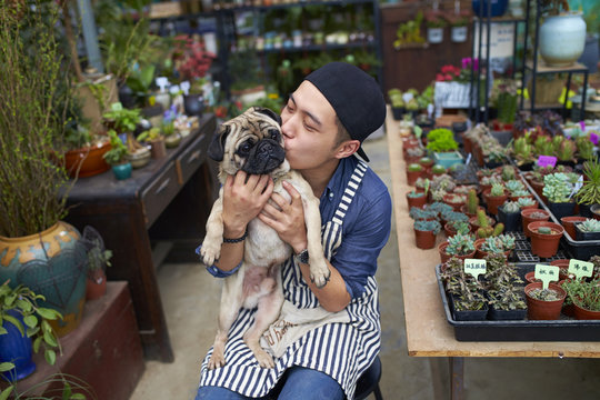 Male Florist Holding His Dog In The Shop