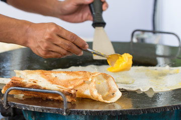 Thai street food of merchant making delicious hot roti for customers