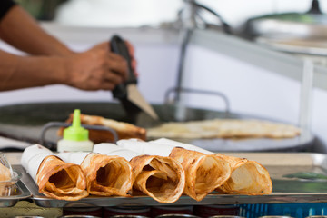 Thai street food of merchant making delicious hot roti for customers