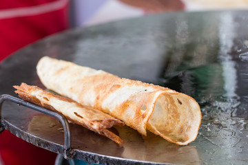 Thai street food of merchant making delicious hot roti for customers