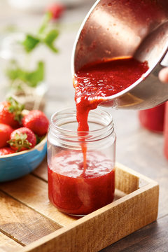 Berry jam pouring into glass can