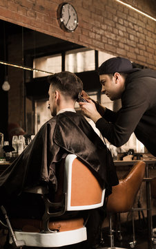Young barber giving client a classic haircut in vintage barber shop