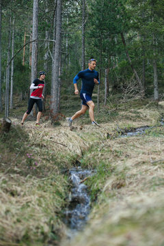 Two people running together in the forest