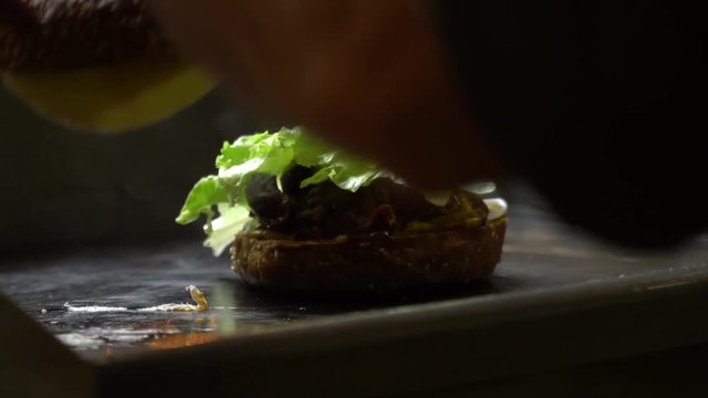 The chef puts the cheese and stove, on top of burge and heats it in the stove. Close up.