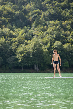 Boy just before jumping into a lake using a springboard