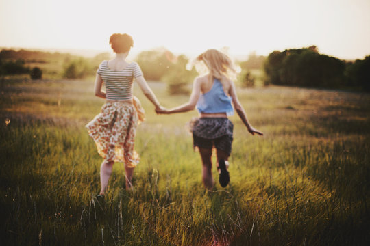 Two female friends run on a field