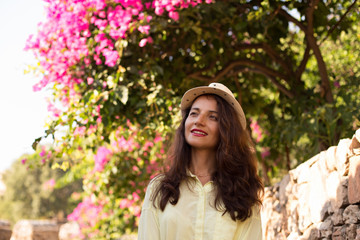 Woman with brown hair and beige hat in front of blossoming bouga