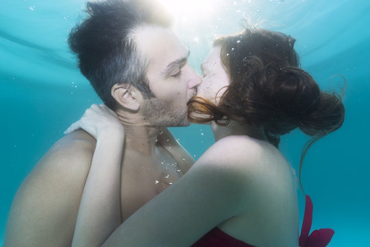 Man and a woman kissing underwater in the swimming pool 