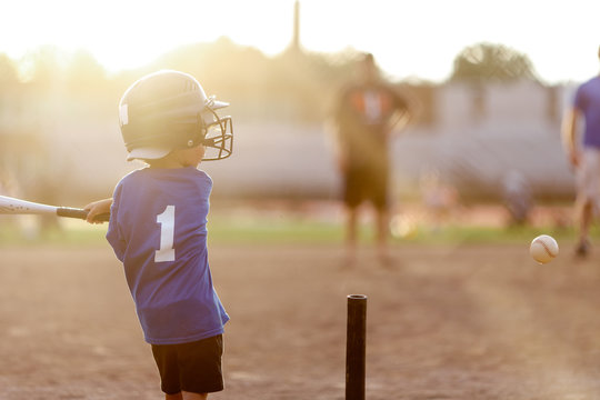 Rear view of a boy playing with t-ball at park