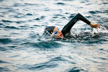 Woman wearing a wetsuit swimming in the sea.