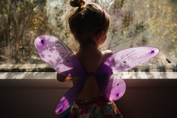 Little girl with butterfly wings in window
