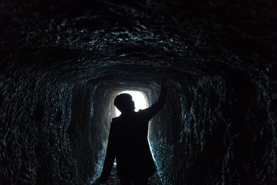 Woman walking through a dark tunnel in the mountains