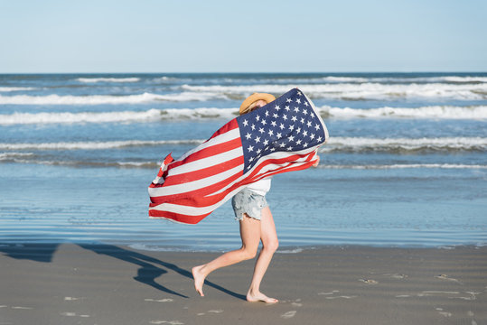 Woman holding American flag while running on the beach