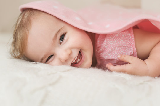 Happy toddler hiding under a blanket