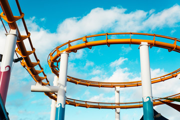 Tracks of orange roller coaster against blue sky