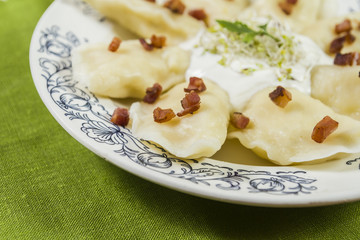 Cooked dumplings with cheese pork scratching and creme fraiche on wooden table.