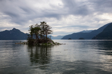 Beautiful rocky island in Howe Sound with mountains in the background. Taken in Furry Creek, North of Vancouver, BC, Canada.