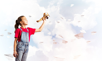 Concept of careless happy childhood with girl throwing retro plane