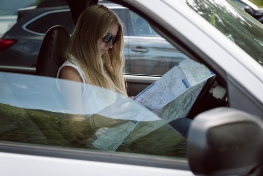 Side view of young woman looking at road map
